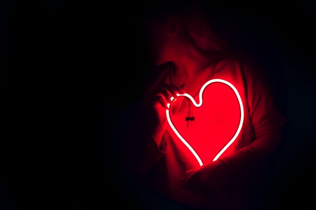 Žena v tme drží pri tele svietiace srdce.jpg